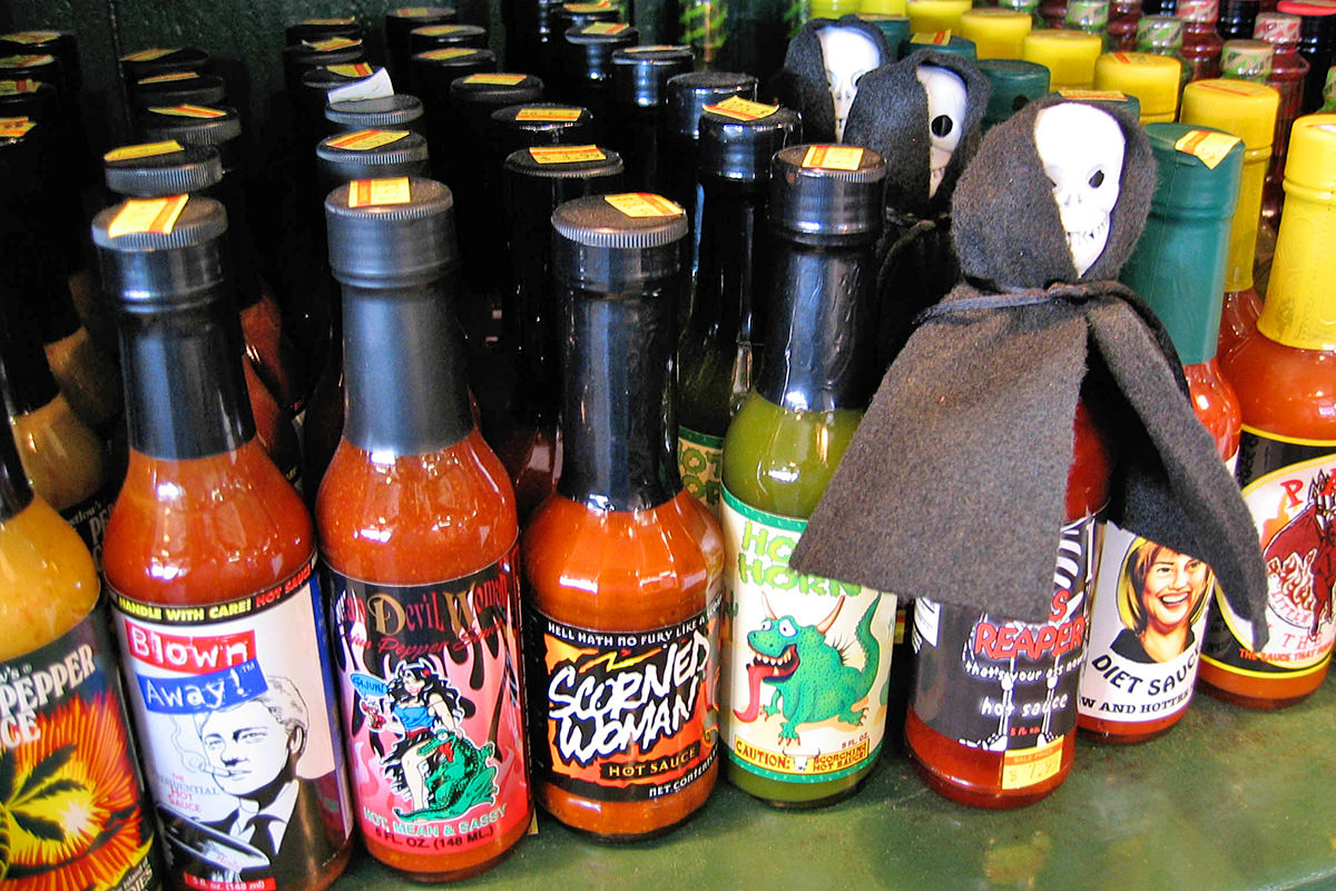 A shelf filled with different hot sauces with clever names like SCORNED WOMAN.