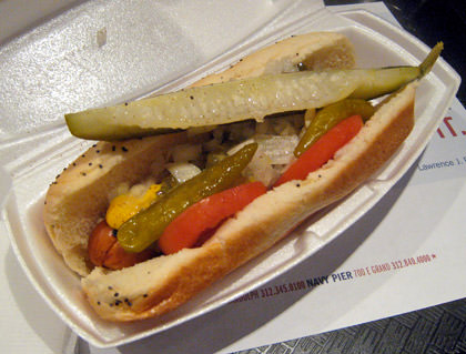 A veggie hot dog decked out Chicago-style with mustard, tomatoes, pickle, peppers, and relish in a steamed poppy-seed bun.