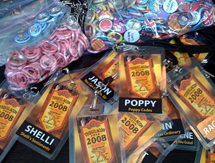 A bunch of TequilaCon Badges on lanyards laying on a table.