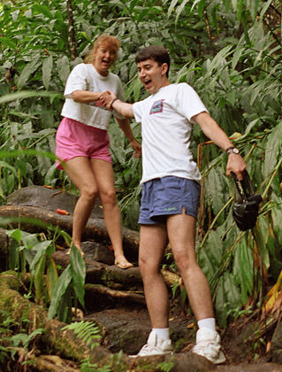Dave wearing short shorts being comically pulled up a Hawaiian jungle trail by a girl.