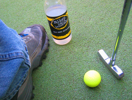 My foot. A golf club. A golf ball.A Mike's Hard Lemonade.