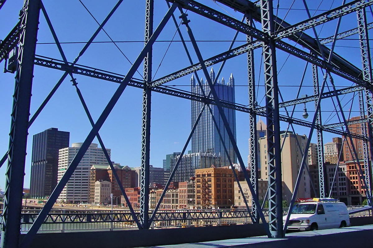 A view from a large metal bridge looking towards downtime Pittsburgh and some beautiful buildings.