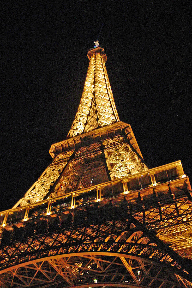 The Eiffel Tower lit up in yellow light at night.