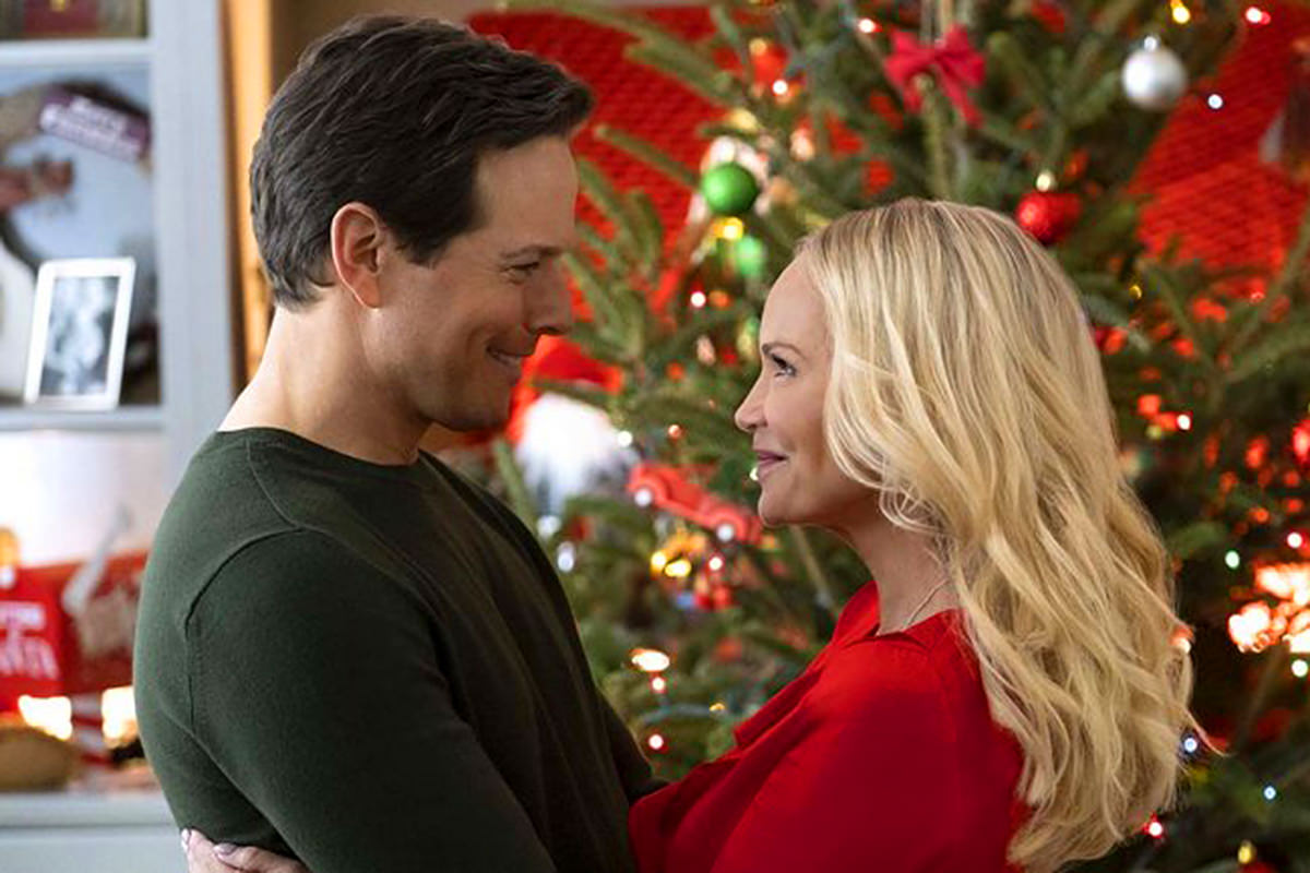 Kristin Chenoweth and Scott Wolf staring into each other's eyes in front of a Christmas tree.