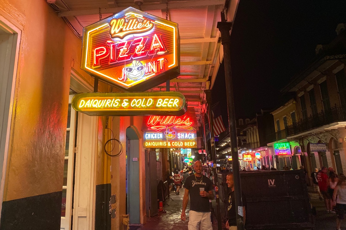 The glowing neon sign for Willie’s Pizza with a glowing Willie’s Chicken sign behind it.