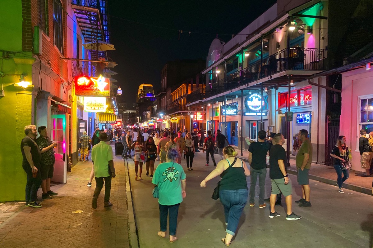 A woman about to fall on her drunk ass as she embraces the madness of Bourbon Street at night.