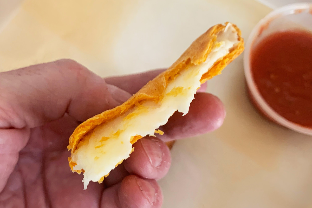 A Cheez-It pizza that's been broken open to show a white cheese center.