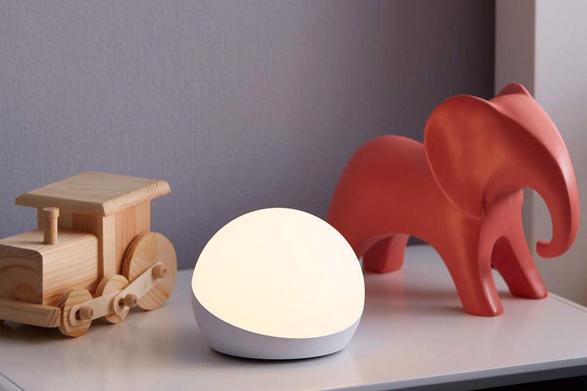 A glowing orb light sitting on a child's dresser with wooden toys around it.