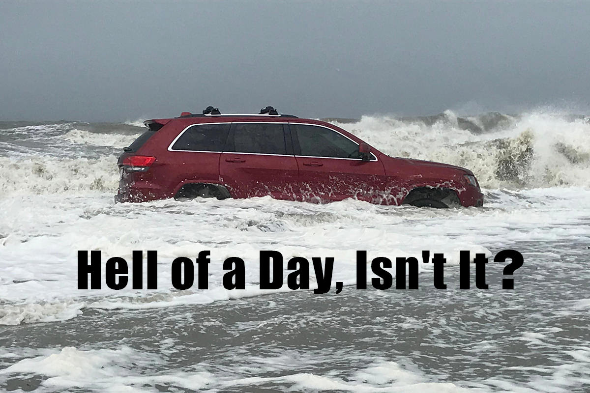 A photo of a red SUV stuck on the beach while waves crash around it... and I've added the text HELL OF A DAY, ISN'T IT? to the bottom.