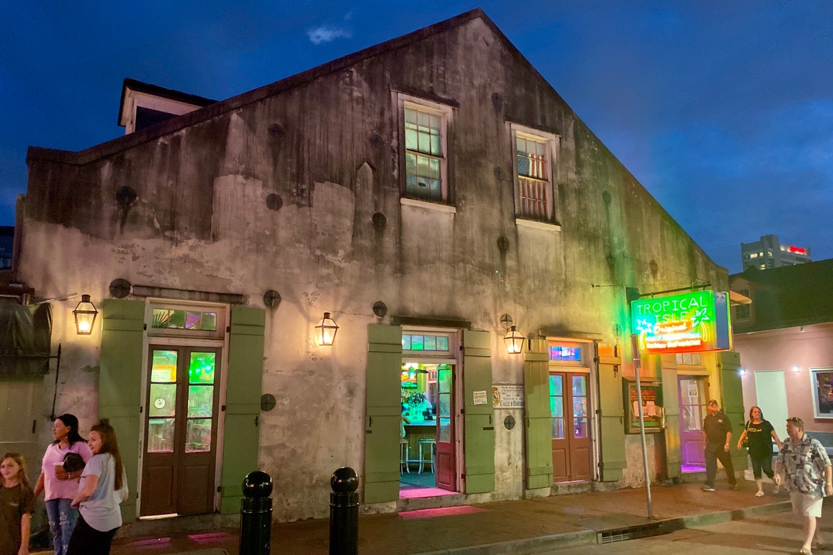 An old cement building with a pointed roof which has been converted to a bar (of course) and it awash in a neon glow.