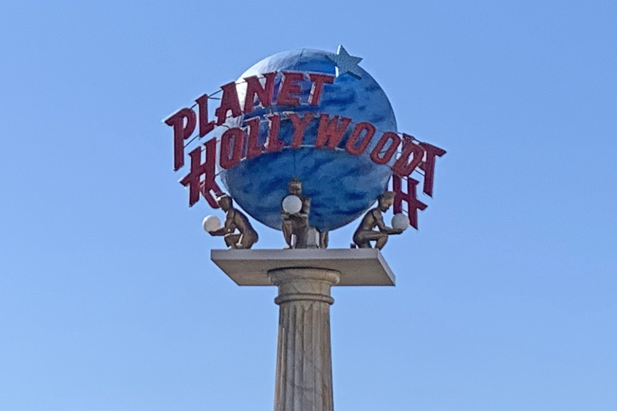 A Planet Hollywood sign at Caesar's Palace against a flawless blue sky.