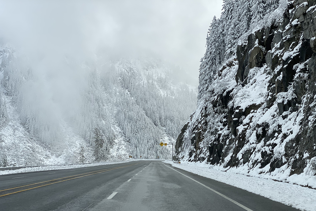 Driving through the mountains with snow-covered trees all around.