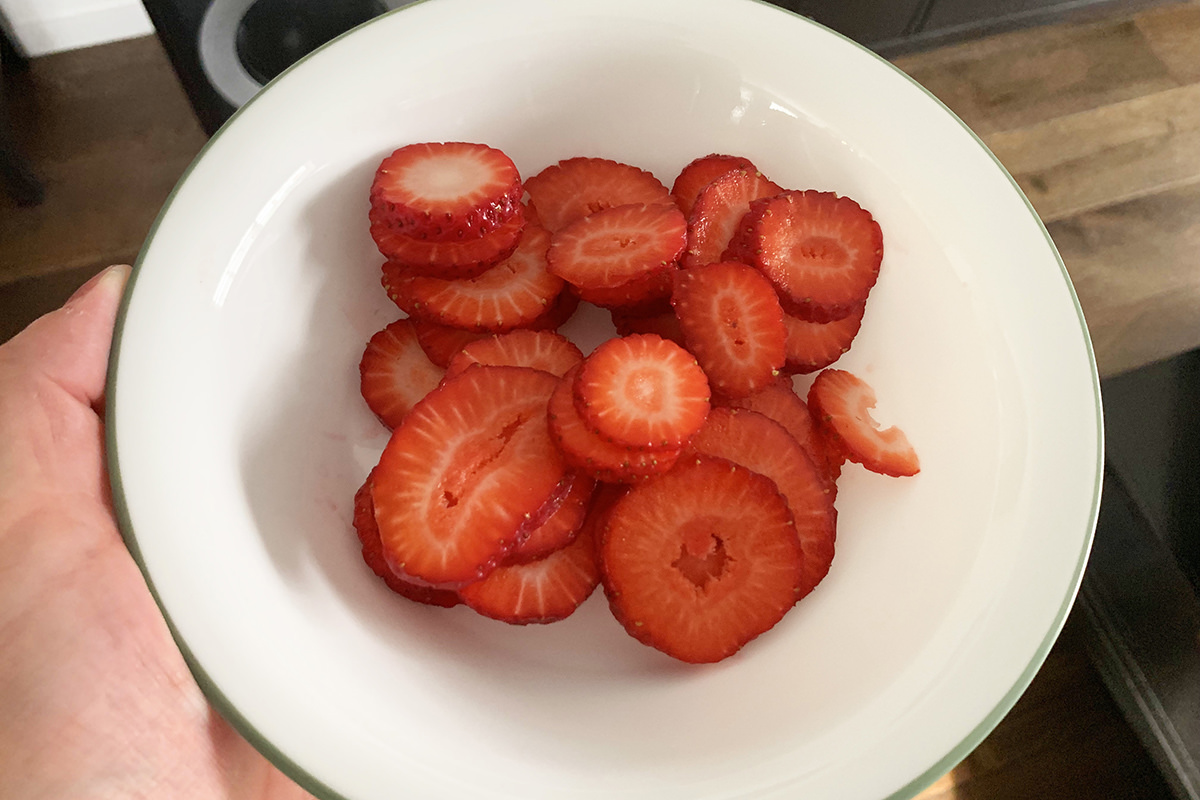 A bowl of beautiful sliced strawberries.