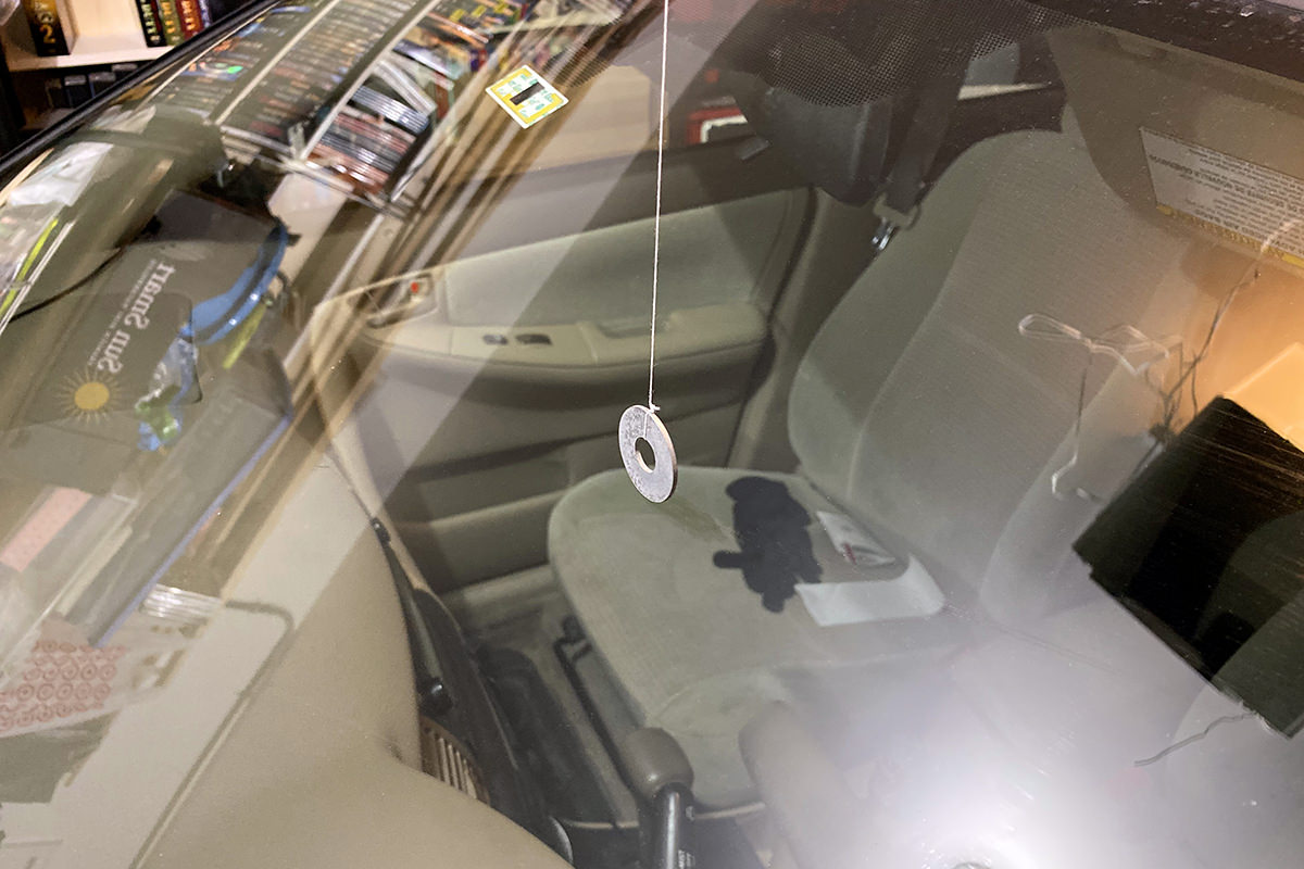 A string on a washer hanging in my garage as seen against my windshield.