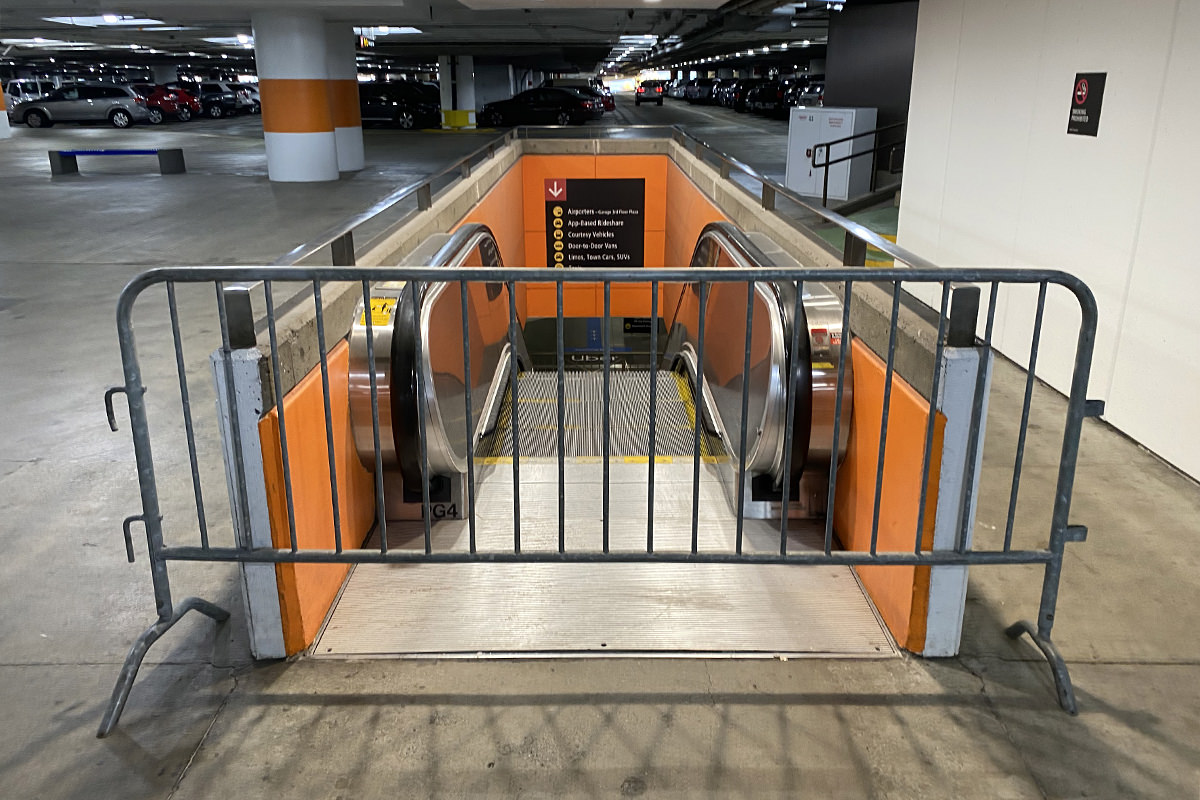 A metal fence in front of an escallator leading down from the parking garage at SeaTac International Airport.