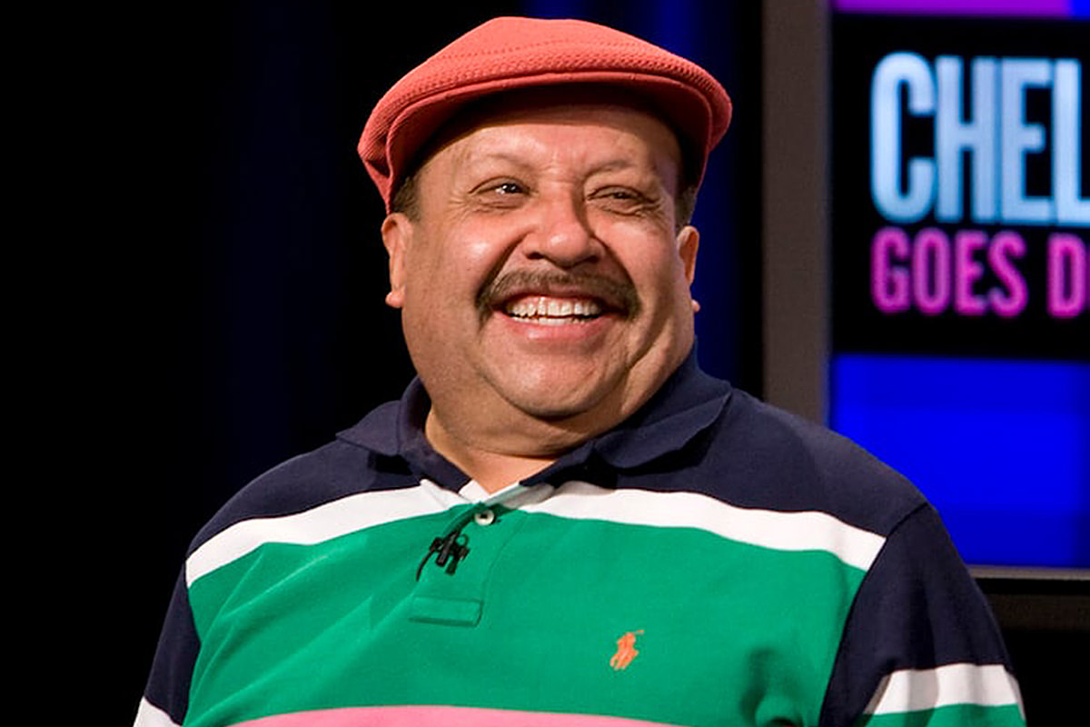 A photo of Chuy Bravo on the Chelsea Lately show wearing a cap and smiling.