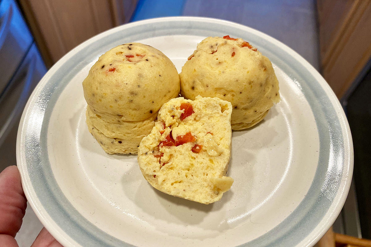 Egg Bites on a plate with one cut in half to show the red peppers inside.