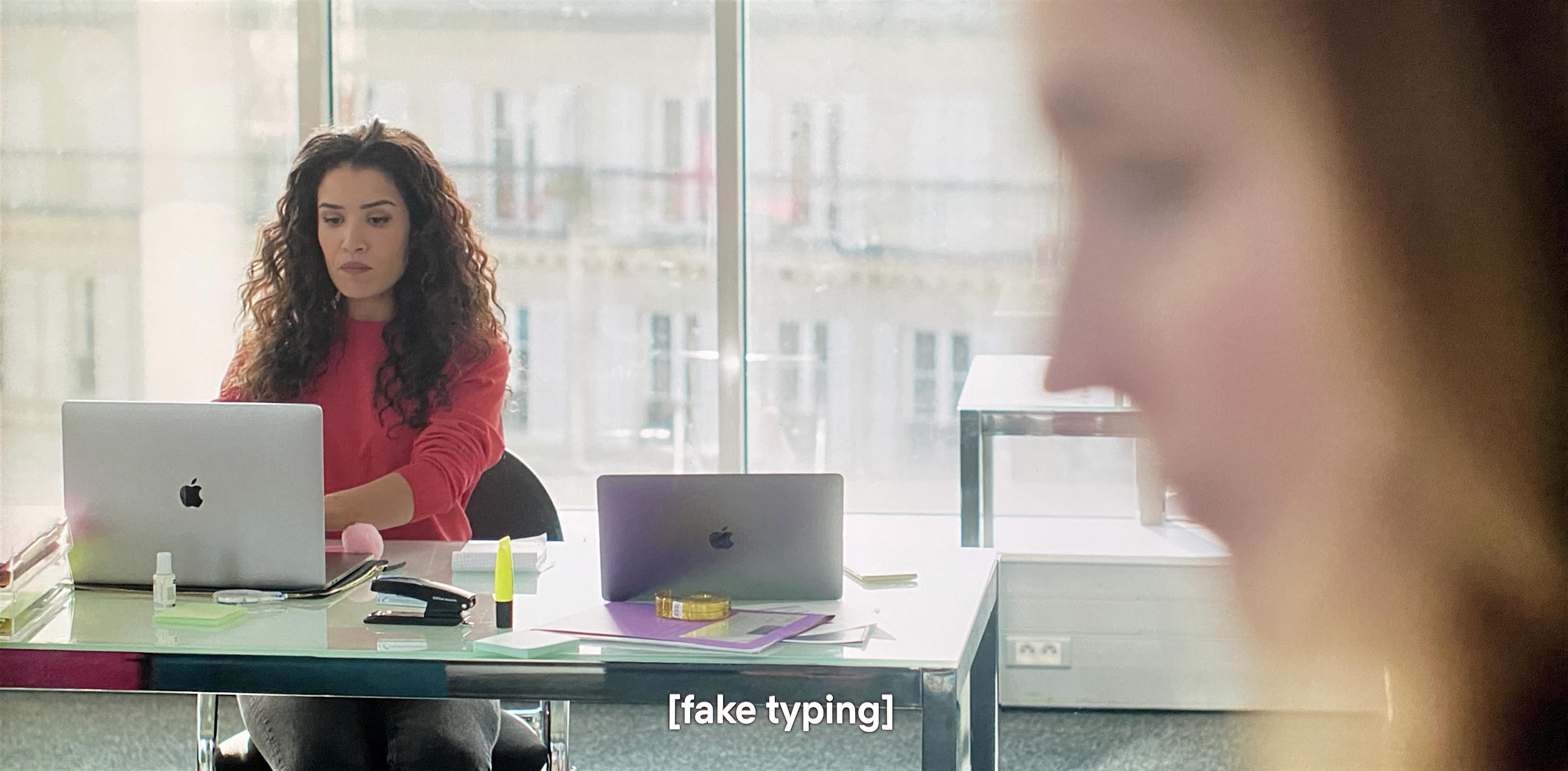 A woman is at a desk pretending to type, her fingers randomly slapping keys.