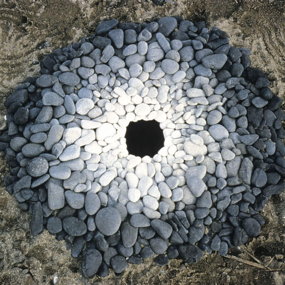 Stones converging in a circle from black to gray to white.