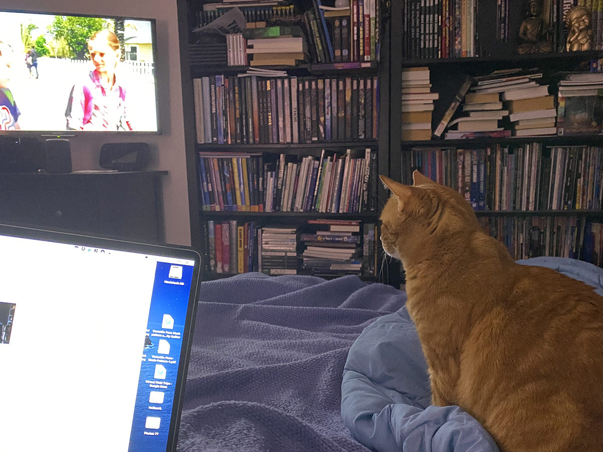 Jenny sitting on my bed watching television.