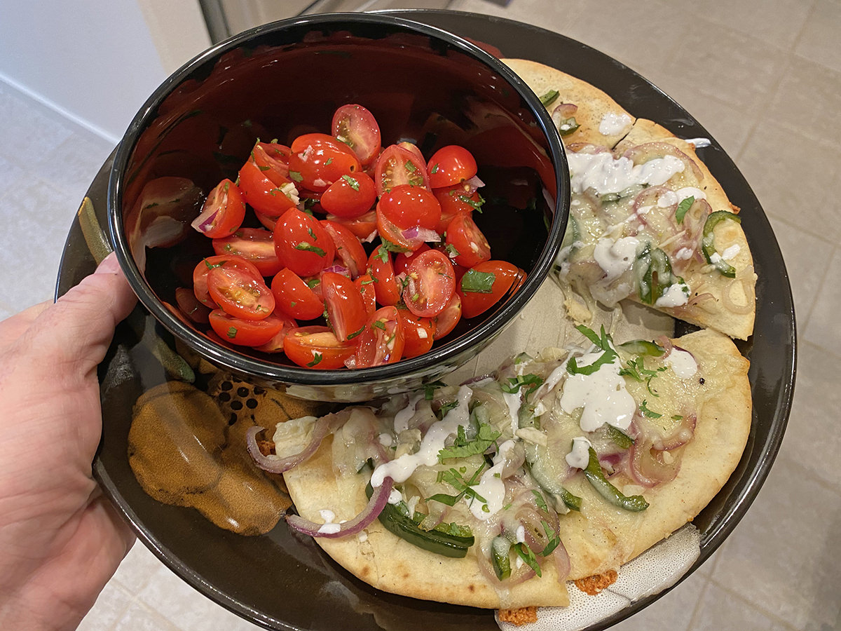 My dinner. It's a pretty bowl of halved cherry tomatoes in a salad with flatbread pizza that has onions and poblanos and melted cheese..