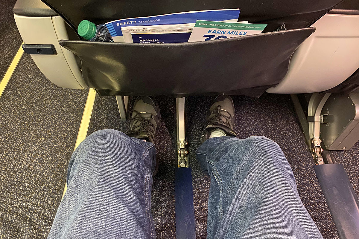 A photo of my legs stretching out in my First Class upgraded seat.