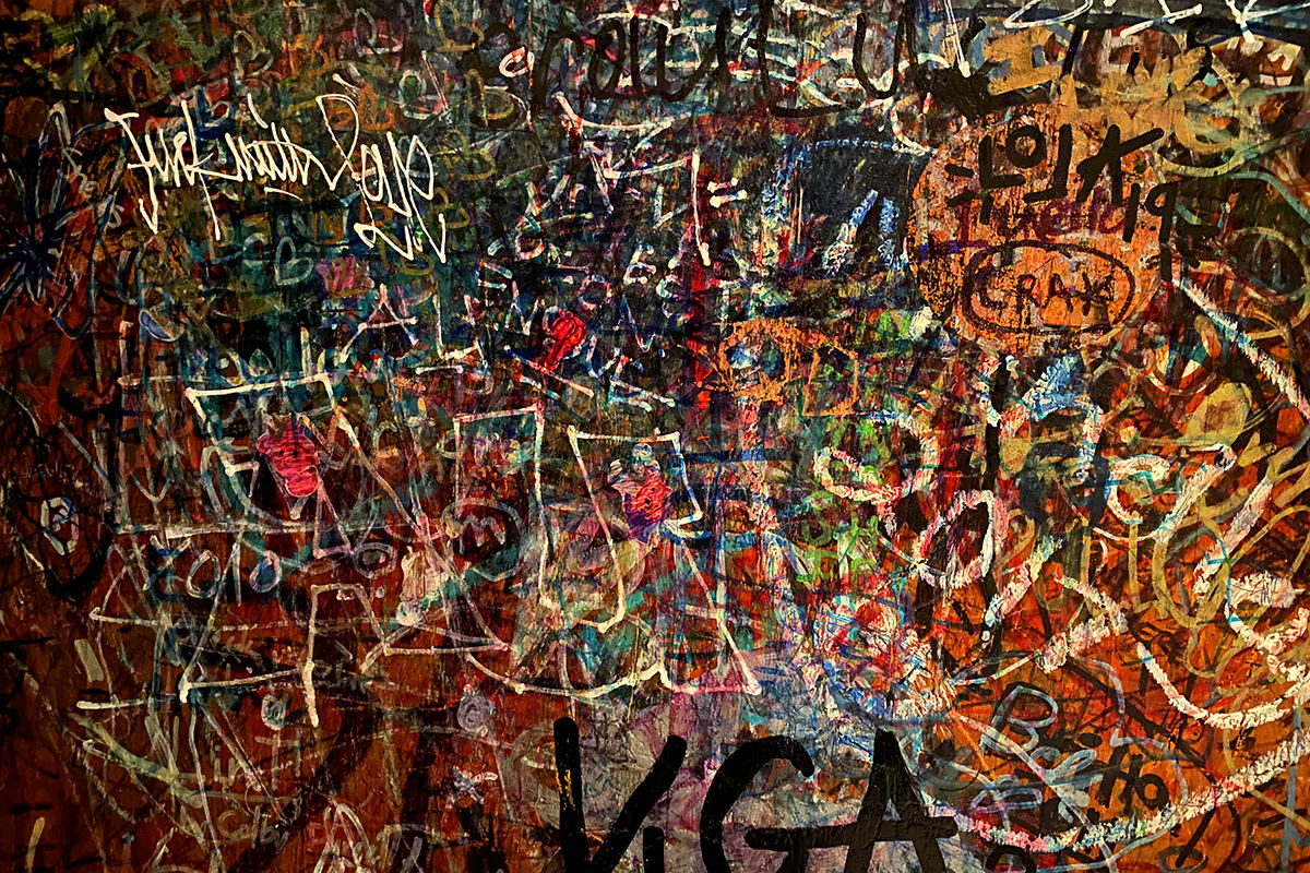 A close-up of a wall with colorful grafitti so thick that you can't even read most of it.