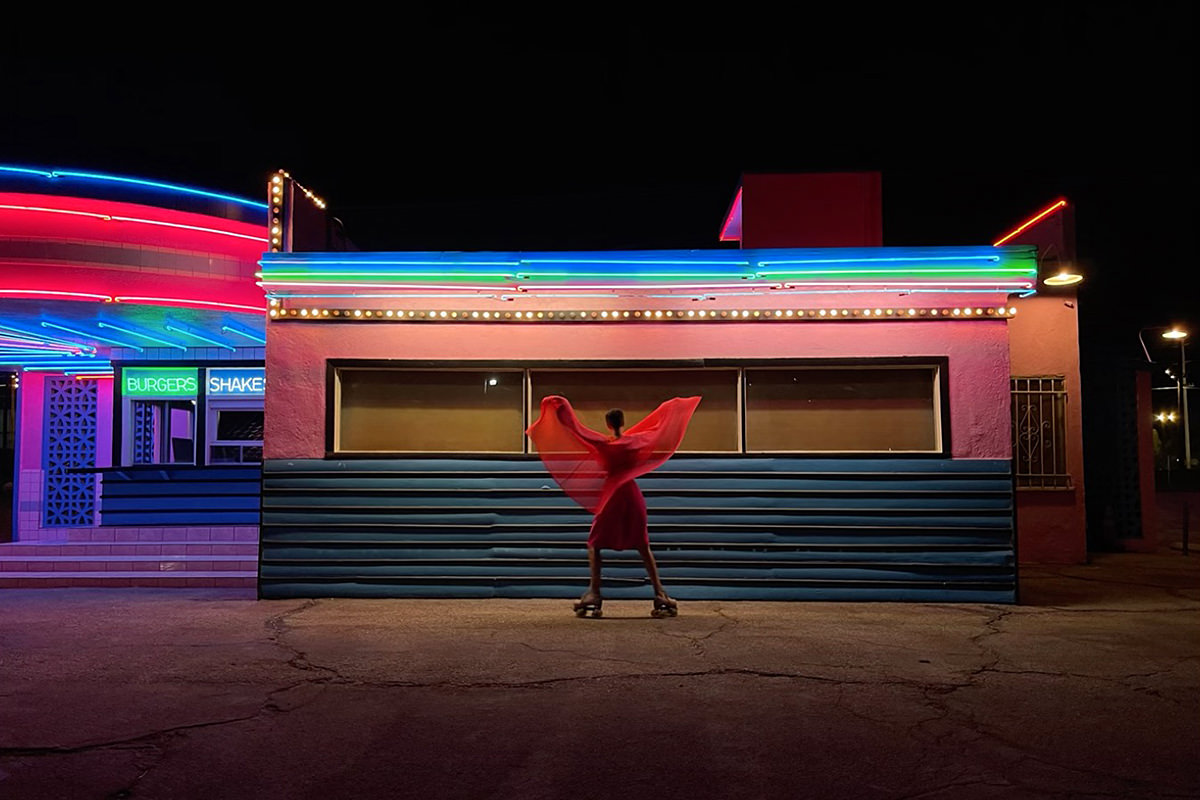 iPhone Sample Photo... A woman dancing in front of neon in a sheer dress.