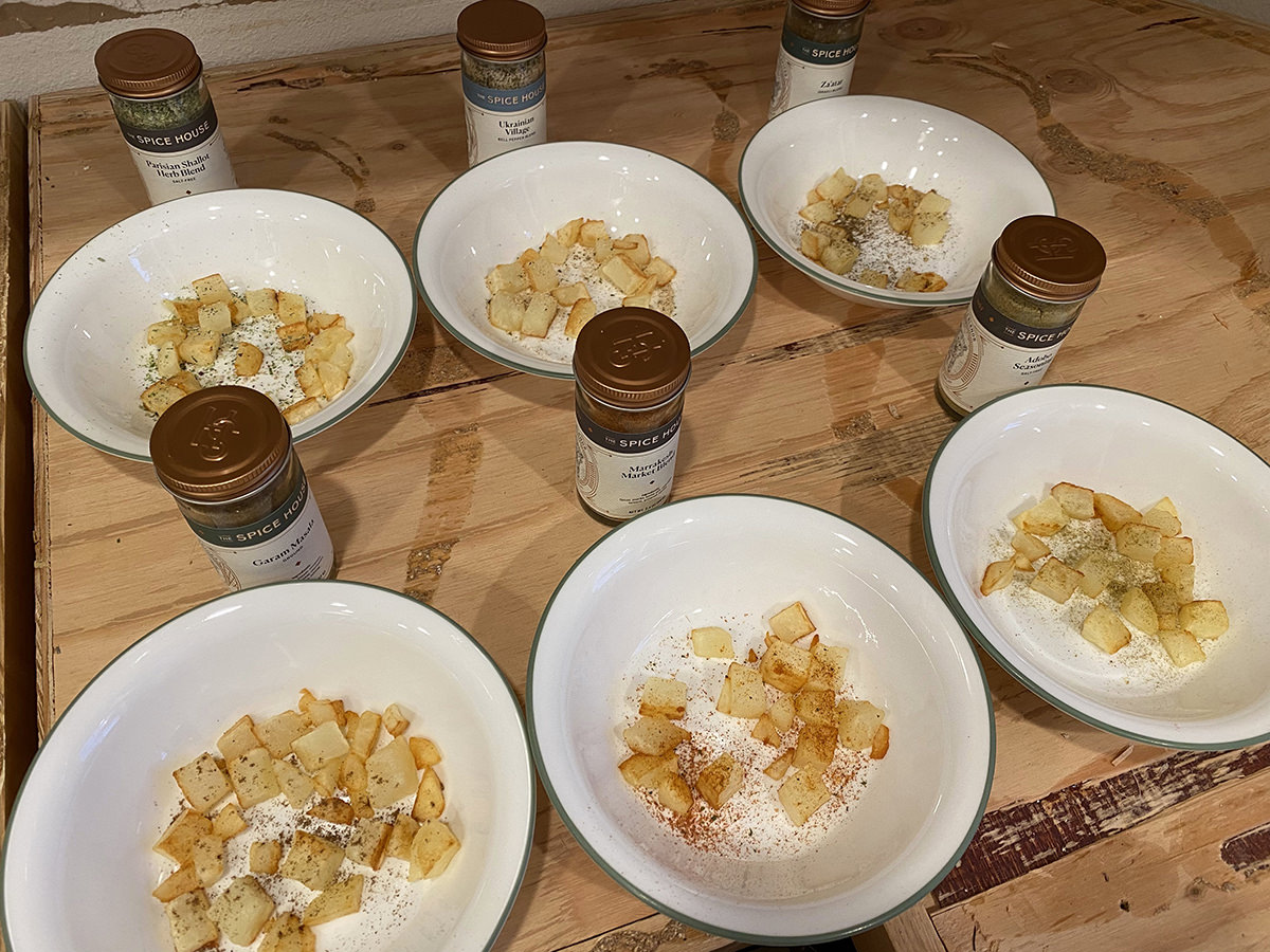 Six bowls of potatoes with various spices on them.