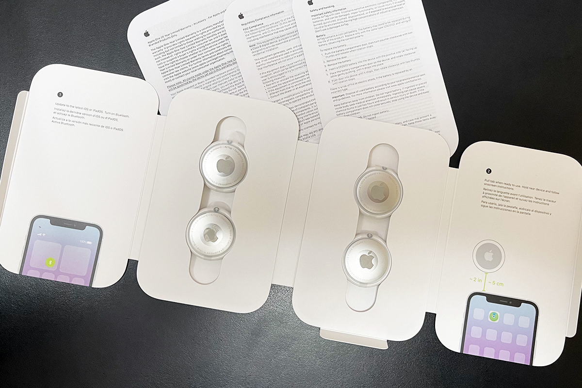 An opened Apple AirTags box with the four AirTags seated in an instruction card.