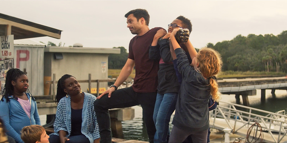 Bucky goofing around with some kids by holding his metal arm out as they try to pulll it down.