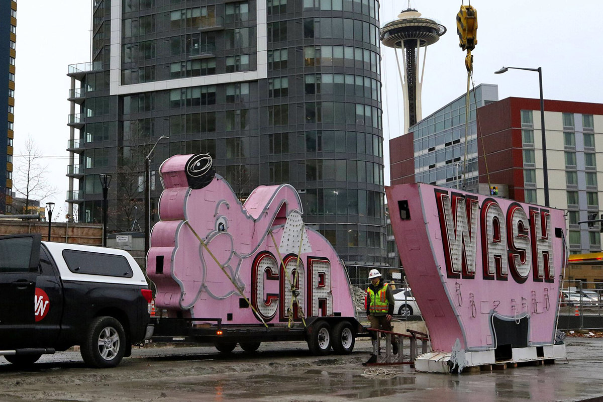 The pink elephant Car Wash sign being cut in half and loaded on a flatbed trailer.