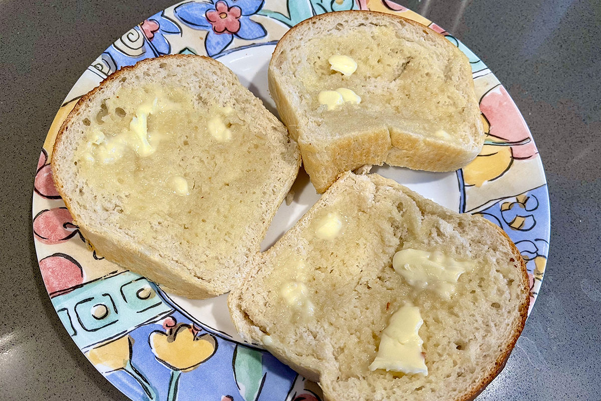 Slices of freshly-baked bread with butter smeared on them.