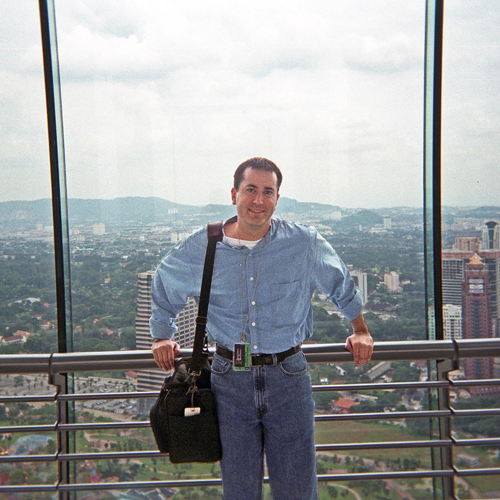 Me standing up in a skyscraper with the city of Kuala Lumpre behind me.