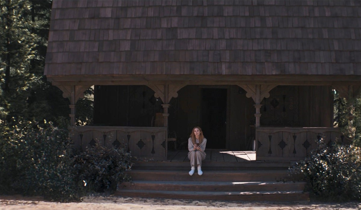 Wanda sitting on the steps of a cabin in the woods.