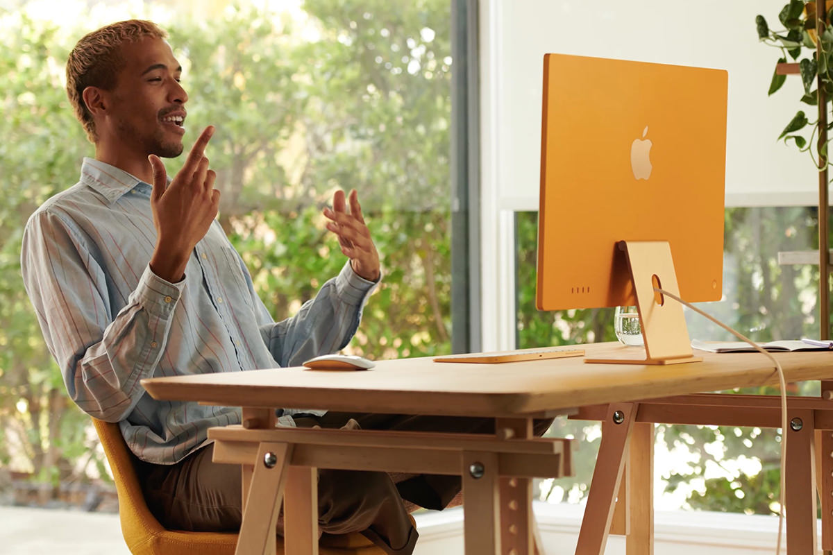 A guy talking on an iMac camera... the Mac is a beautiful yellow color.