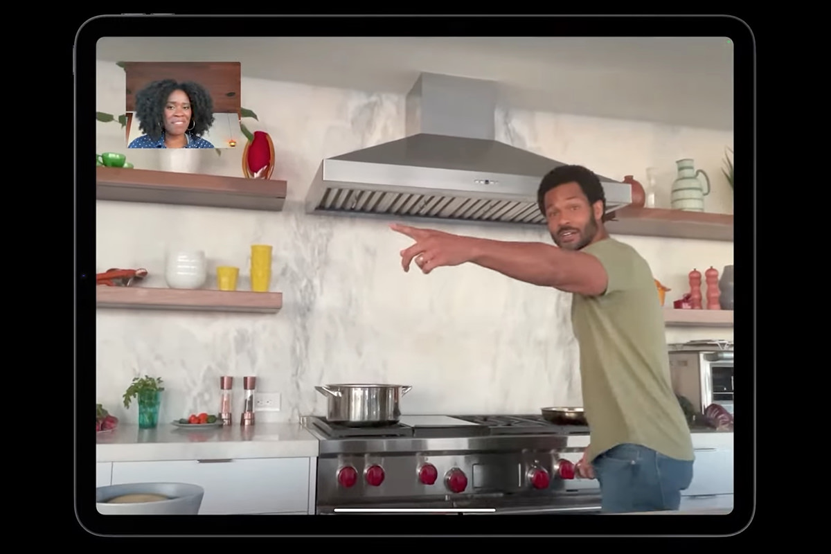 A guy cooking in a kitchen while the iPad camera pans over to where he's at.