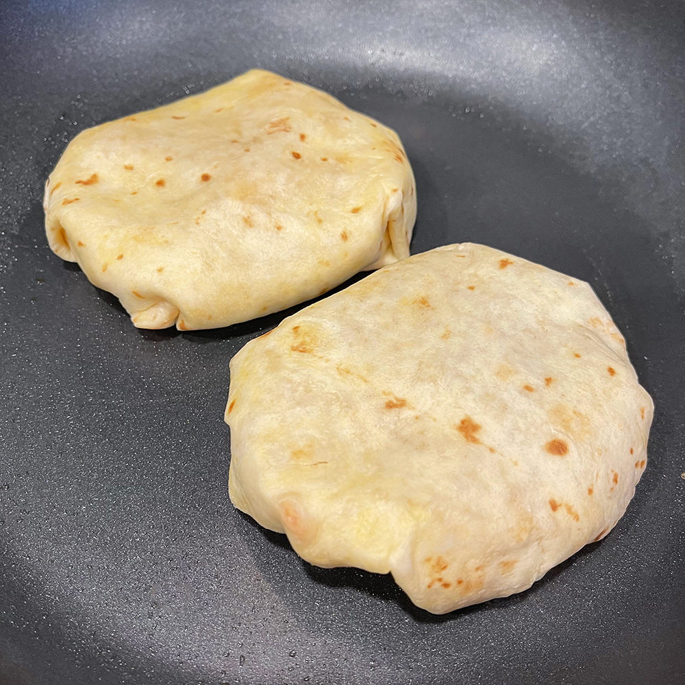 The torilla wrapped around the ingredients and flipped in the pan.