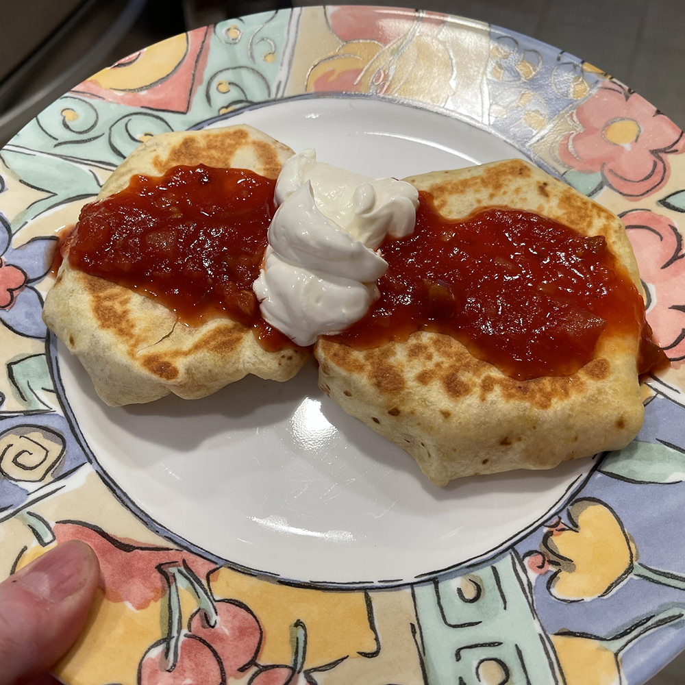 The Crunchwraps on a plate with salsa and sour cream on top.