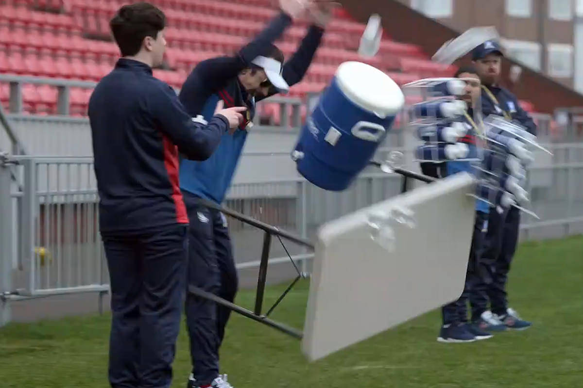 Ted flips over a table of sports drinks.