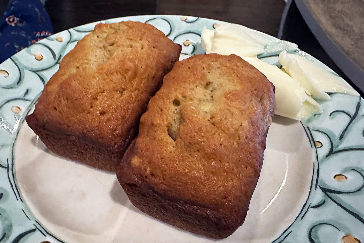 Mini loaves of banana bread on a plate with plant butter.