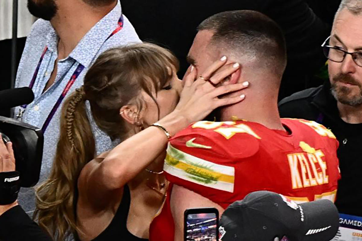 Taylor Kissing Travic Kelce on the field after their Super Bowl win.