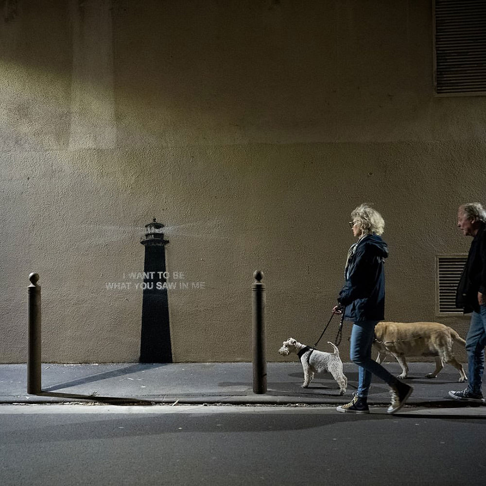A couple walking in front of the new Banksy with their dogs.